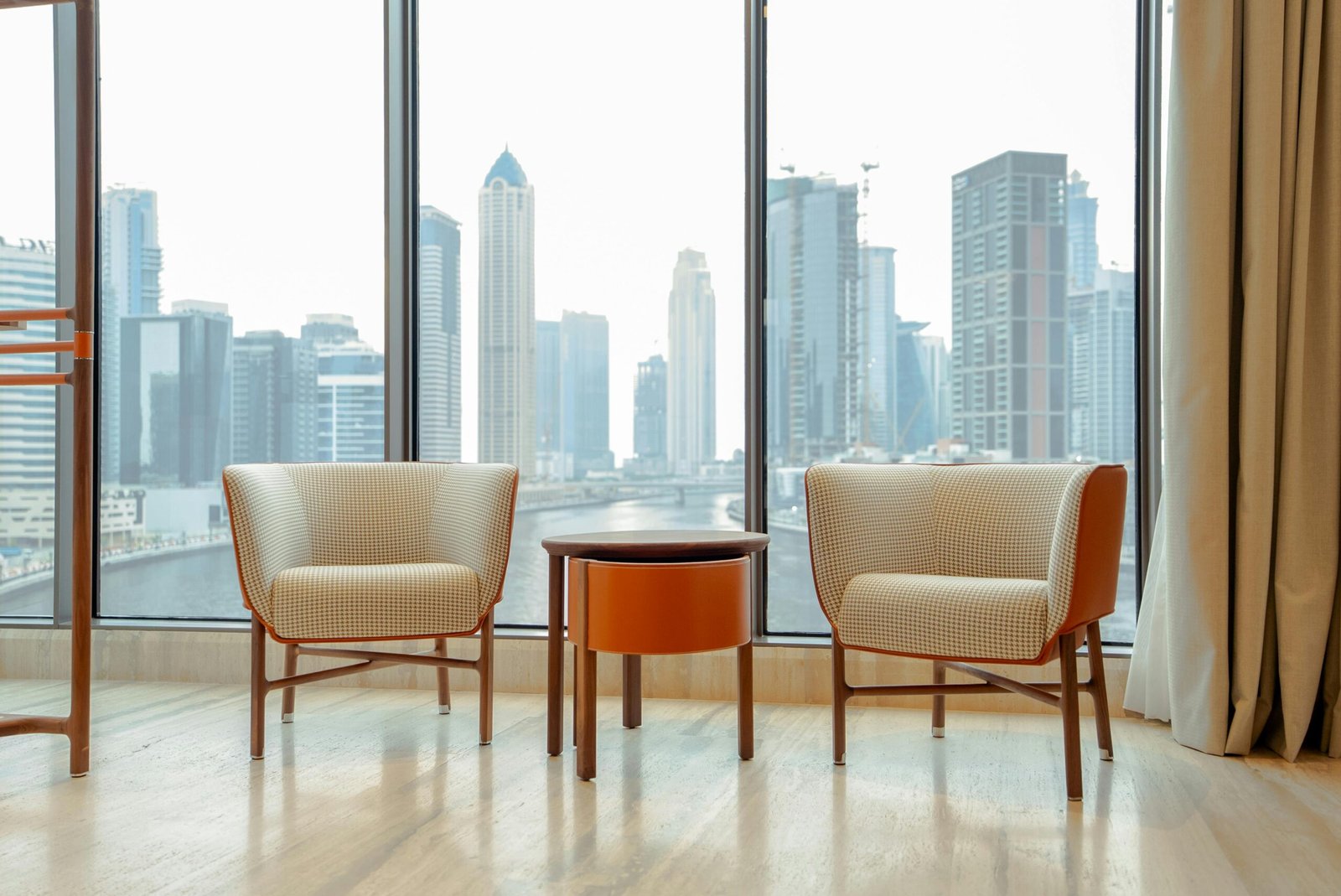 Stylish apartment interior featuring a city skyline view with elegant seating and large windows.